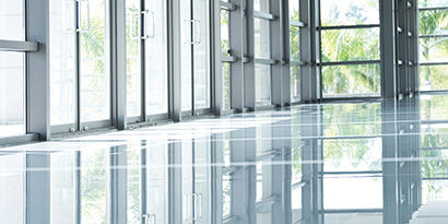 A shiny floor in a bright room with floor-to-ceiling windows.
