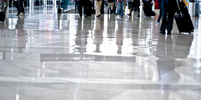 The reflection of people walking on a clean high-traffic hallway.
