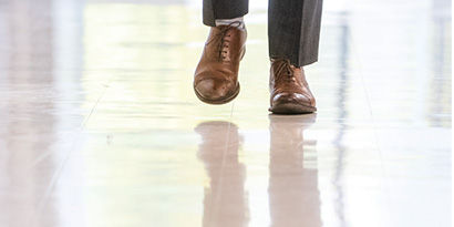An individual in dress shoes walking on a shiny coated floor.