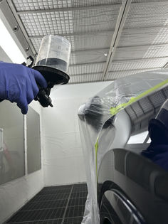 Spray Gun equipped with 3M™ PPS™ Basic Series System applying clear coat to car part in paint booth - 1