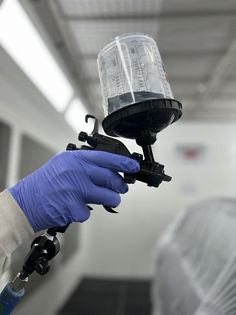 Spray Gun equipped with 3M™ PPS™ Basic Series System applying clear coat to car part in paint booth - 7