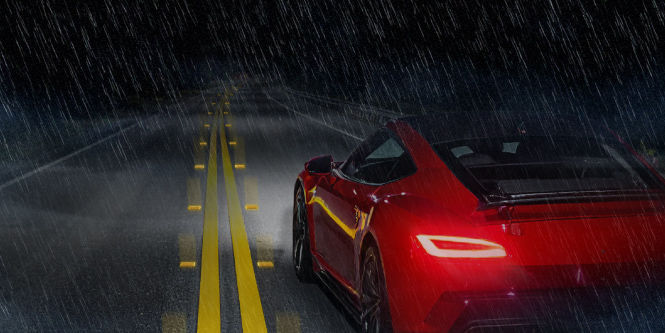 Red coupe driving on a wet night road with RPM reflecting light.