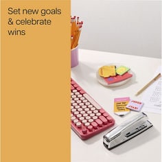 Image of the top of a desk with a keyboard to the left with a stapler and a plate full of Post it® class notes. Reader: Set new goals & celebrate wins