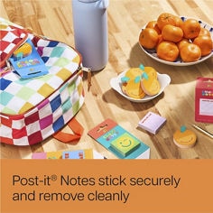 Render of table top with oranges, orange Post-it® notes, class notes and a school bag. Reader: stick securely, and remove cleanly.