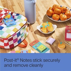 Render of table top with oranges, orange Post-it® notes, Lunch notes and a school bag. Reader: stick securely, and remove cleanly.