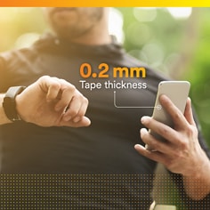 Lifestyle image of a person holding a phone with thickness callout for the tape. 0.2 mm tape thickness.