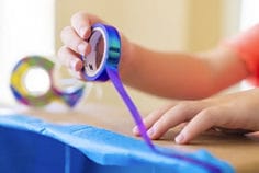Photograph of kids hands using kids tape for craft project.