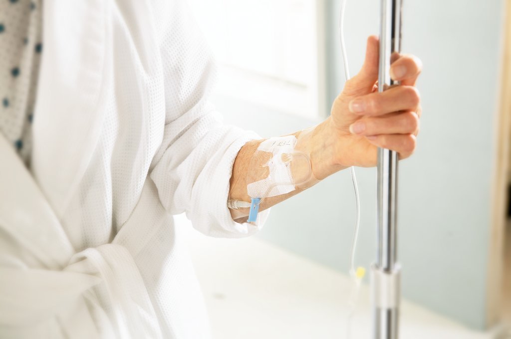 person holding onto a metal IV pole with a PVAD.