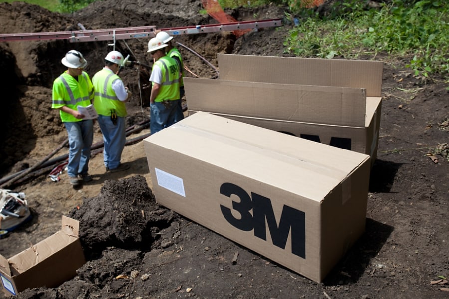 Workers installing electrical splice with 3M box on the ground