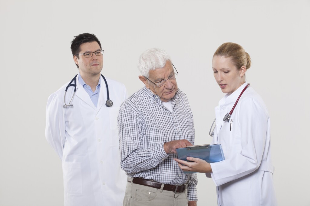 A male and female doctor showing an older male patient a medical chart