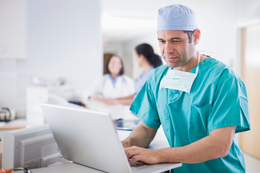 Un médecin qui examine un dossier médical sur un ordinateur portable.